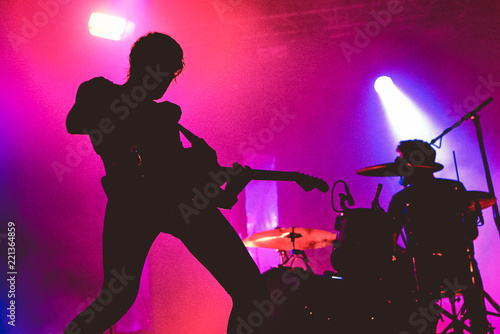 Silhouette of an unrecognizable male guitarist in a pink background
