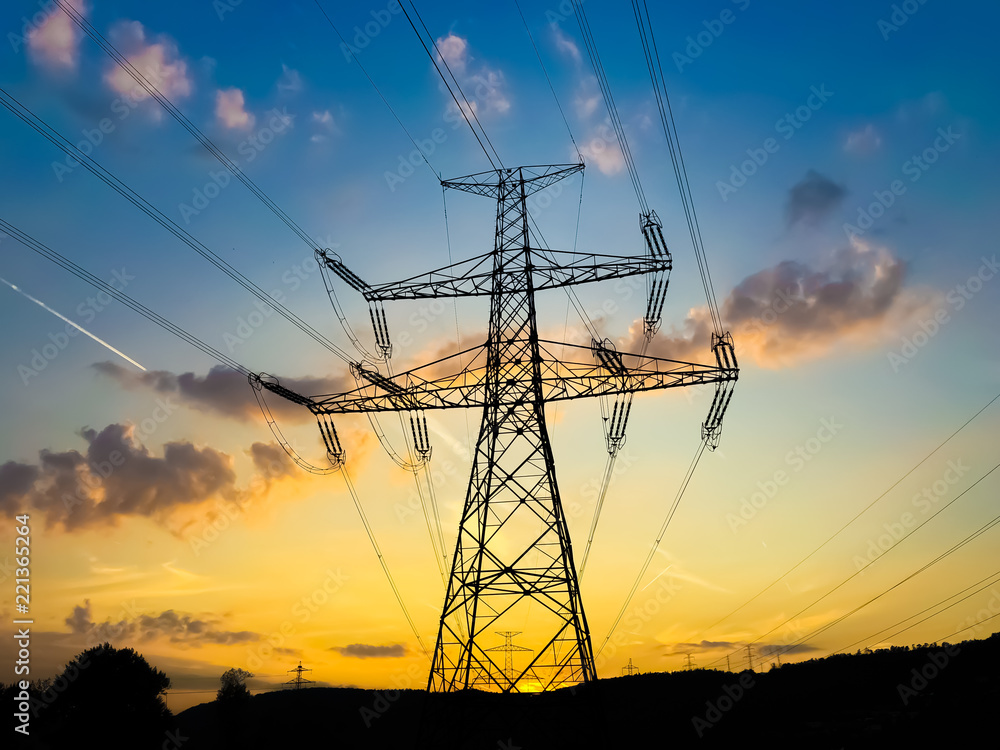 Electricity tower during golden sunset with blue sky and small clouds
