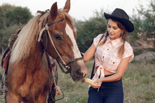 girl in cowboy black hat shirt jeans with horse