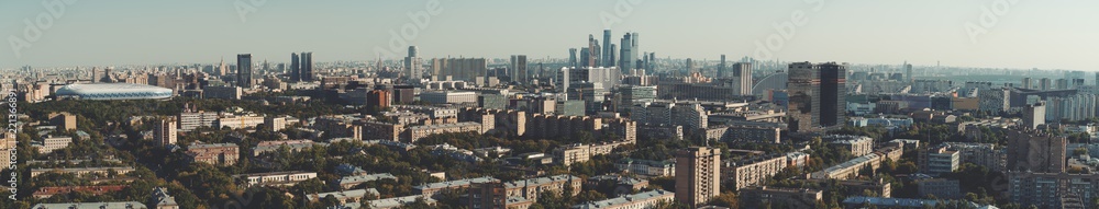 Panorama of evening summer cityscape with the residential district and dwelling houses in the foreground, multiple office skyscrapers and business high-rises in the distance; huge stadium on the left