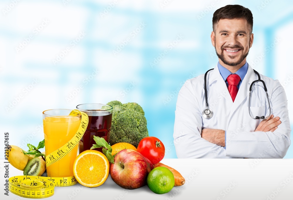 Young handsome dietology specialist with healthy food on table Young handsome dietology specialist with healthy food on table