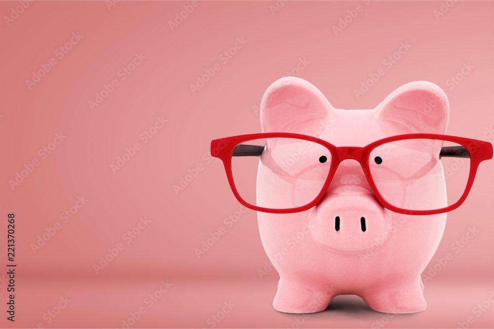 Piggy bank in glasses on background Piggy bank in glasses on background