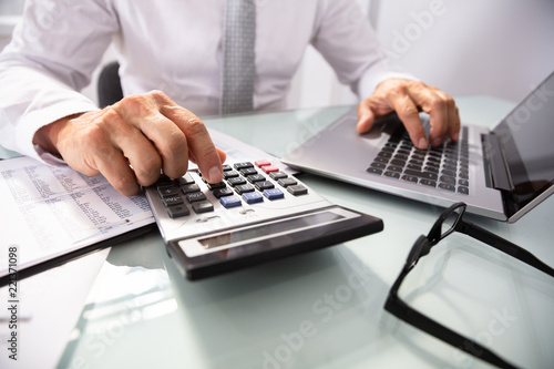 Businessman Using Laptop And Calculator