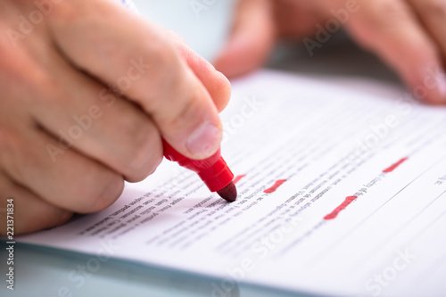 Businessperson Marking Error With Marker On Document