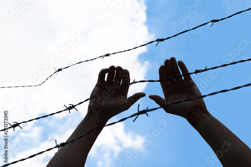 Refugee Holding Barbed Wire Fence
