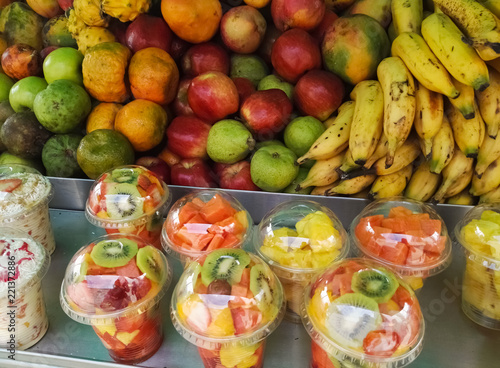 Tropical fruit sales stand. Apples  pears  bananas  tangerines and pitahayas. Fruit salad in plastic bottles with kiwi  papaya and pineapple. Delicious  nutritious and juicy.