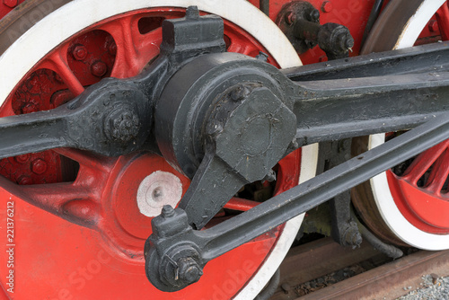 Old steam train wheels approaching, close-up. Black and red wheels. Rails and sleepers.