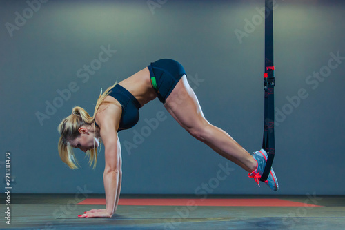 Sporty woman doing TRX exercises in the gym