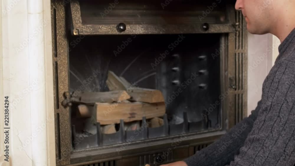 4k video of young man opening fireplace glass door and putting wooden logs inside 4k video of young man opening fireplace glass door and putting wooden logs inside