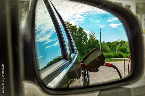 Reflected in the side mirror of a car of fuel nozzle to refill © tinkerfrost