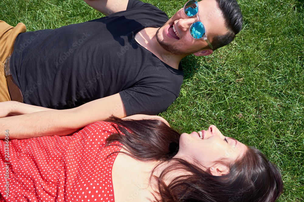 Young caucasian lovely couple or college students lying down on the grass together Young caucasian lovely couple or college students lying down on the grass together