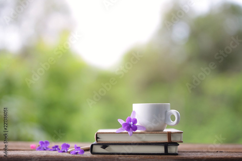 White cup and notebook with flower at outdoor