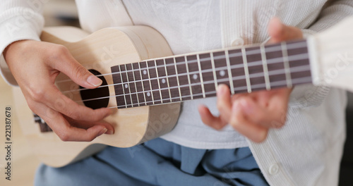 Woman play song on ukulele at home