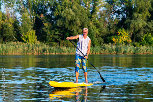 Strong man is training on a SUP board on large river
