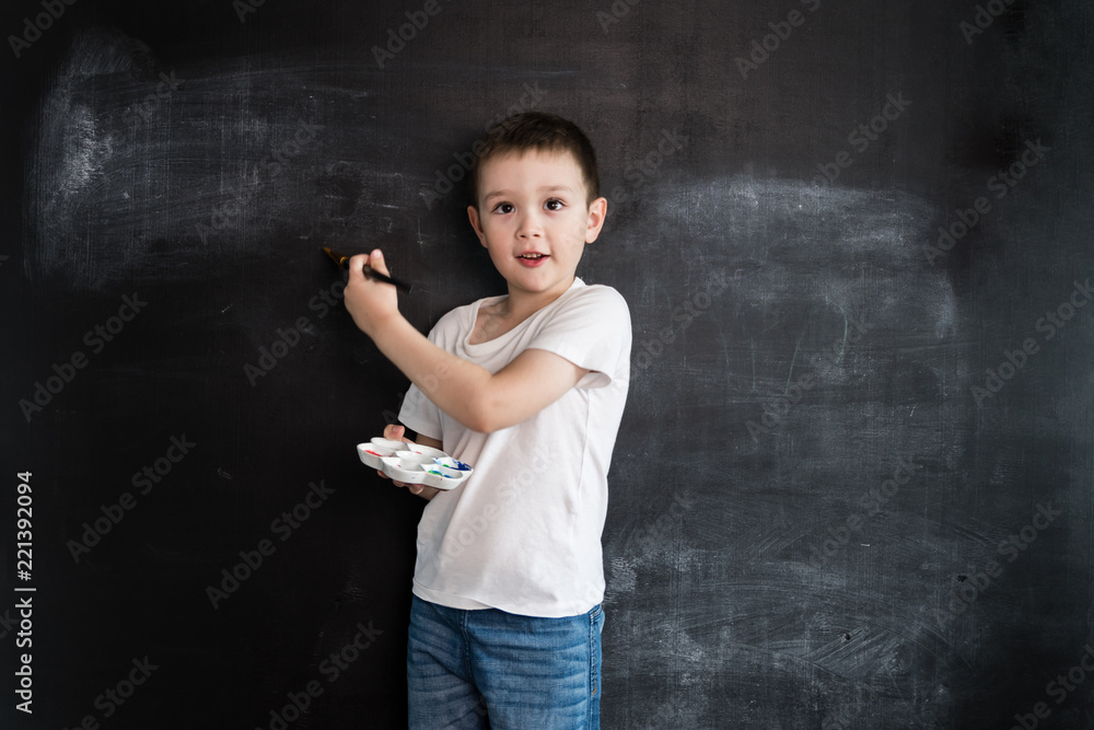 Young boy's standing with palette and brush in his hands near blackboard. Young artist. Creative design concept for 2019 calendar. Young boy's standing with palette and brush in his hands near blackboard. Young artist. Creative design concept for 2019 calendar.