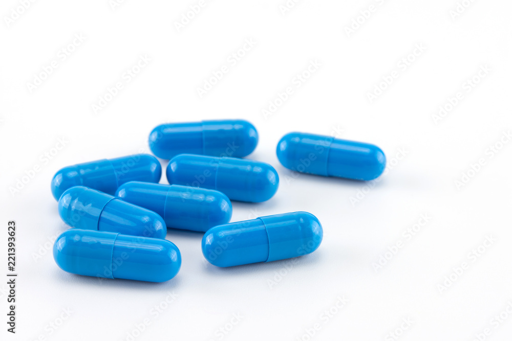 blue capsules of medicine on white background; selective focus.