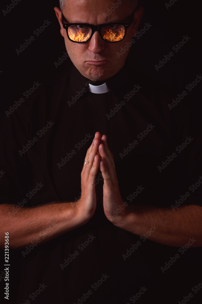 priest with a reflection of fire in glasses