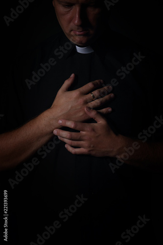 priest prays in a cassock