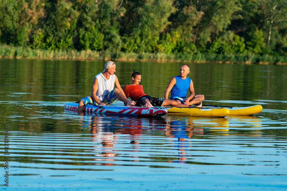 Happy friends, a SUP surfers relax on the big river Happy friends, a SUP surfers relax on the big river