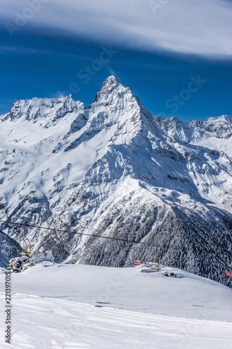 Mt. Mussa-Achitara ski slope against Mt. Belalakaya in winter sunny day. Dombai ski resort, Karachai-Cherkess, Western Caucasus, Russia.