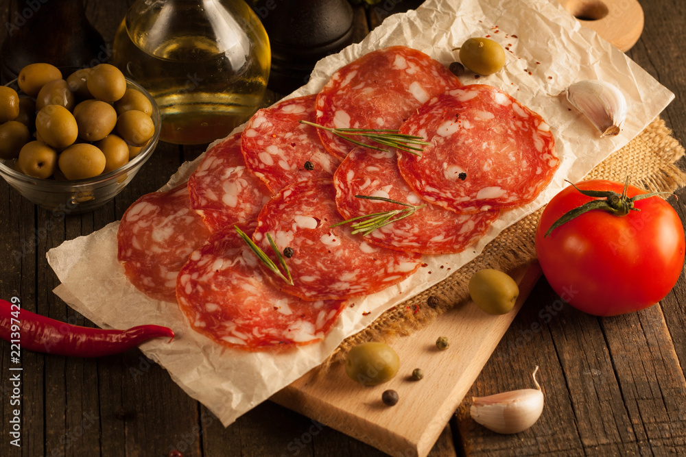 Chorizo sausage and salami, thin cut. spanish salami on the wood background with spices, paprika, pepper. Spicy food. Garlic, tomato, salad background. Chorizo sausage and salami, thin cut. spanish salami on the wood background with spices, paprika, pepper. Spicy food. Garlic, tomato, salad background.