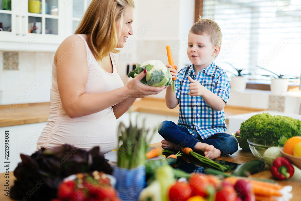 Pregnant mother and son preparing meal Pregnant mother and son preparing meal