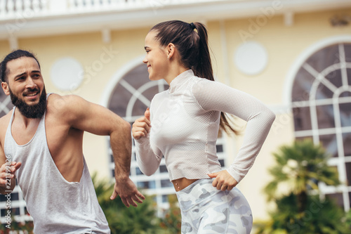 fitness, sport, people and lifestyle concept - happy couple in sport apparel running outdoors in urban area photo