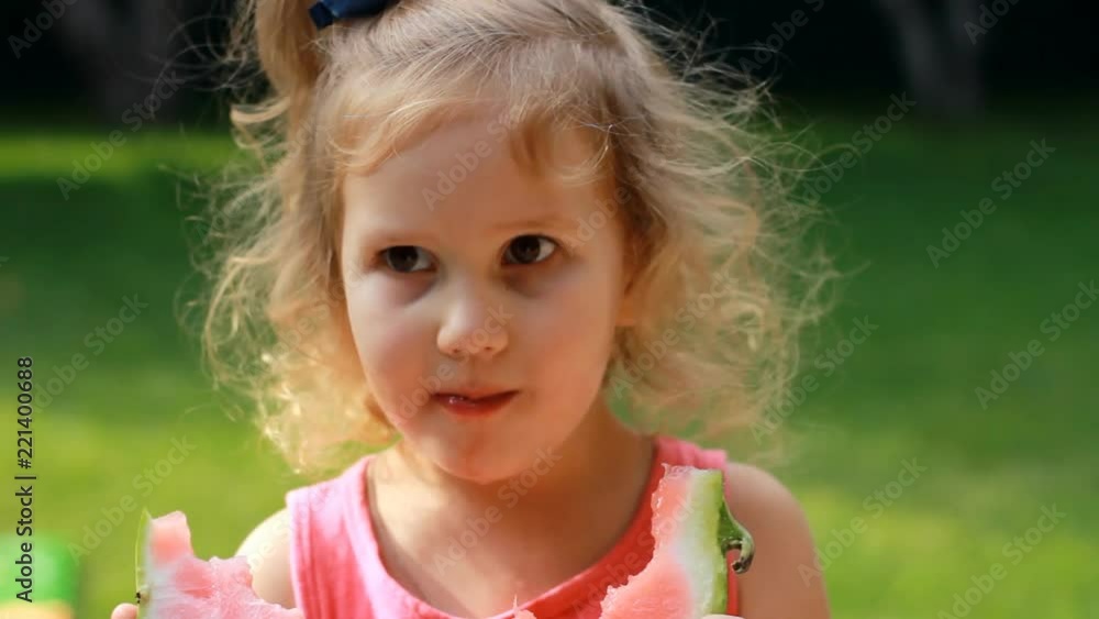 Child girl eats a watermelon. Baby eating food in summer. Close-up portrait Child girl eats a watermelon. Baby eating food in summer. Close-up portrait