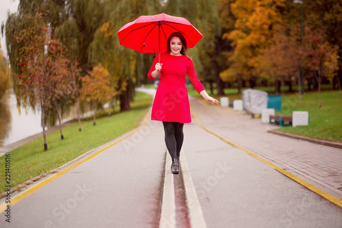 happy girl walks in the autumn park under an umbrella