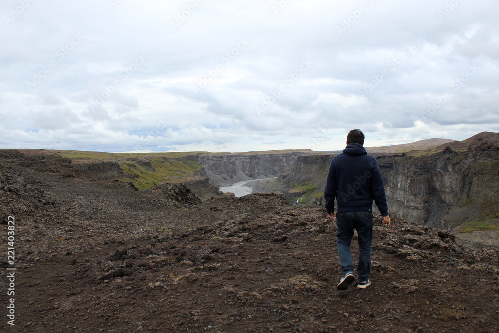 Man looking at Waterfall in iceland from above: icelandic landscape in a cloudy day Man looking at Waterfall in iceland from above: icelandic landscape in a cloudy day