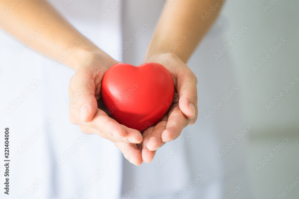 Female nurse holding a red heart shape. Health care insurance and love concept
