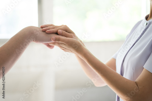 Nurse holding the hand of a patient man, showing sympathy and kindness