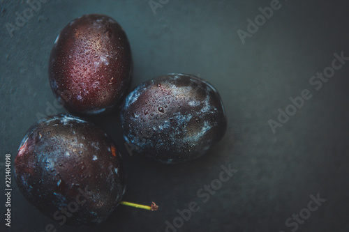 hree plums on a dark background photo