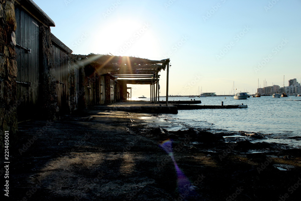 Sunset silhouette: woman dancing in fish shack. San Antonio de Portmany, Ibiza.
