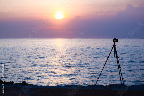 Dslr digital professional camera stand on tripod photographing sea, twilight sky and cloud landscape. 