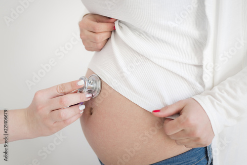 Pregnant woman being examine by a doctor with a stethoscope.