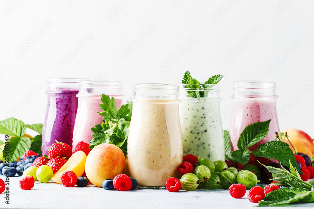 Healthy and useful colorful berry cokctalis, smoothies and milkshakes with yogurt, fresh fruit and berries on gray table, selective focus Healthy and useful colorful berry cokctalis, smoothies and milkshakes with yogurt, fresh fruit and berries on gray table, selective focus