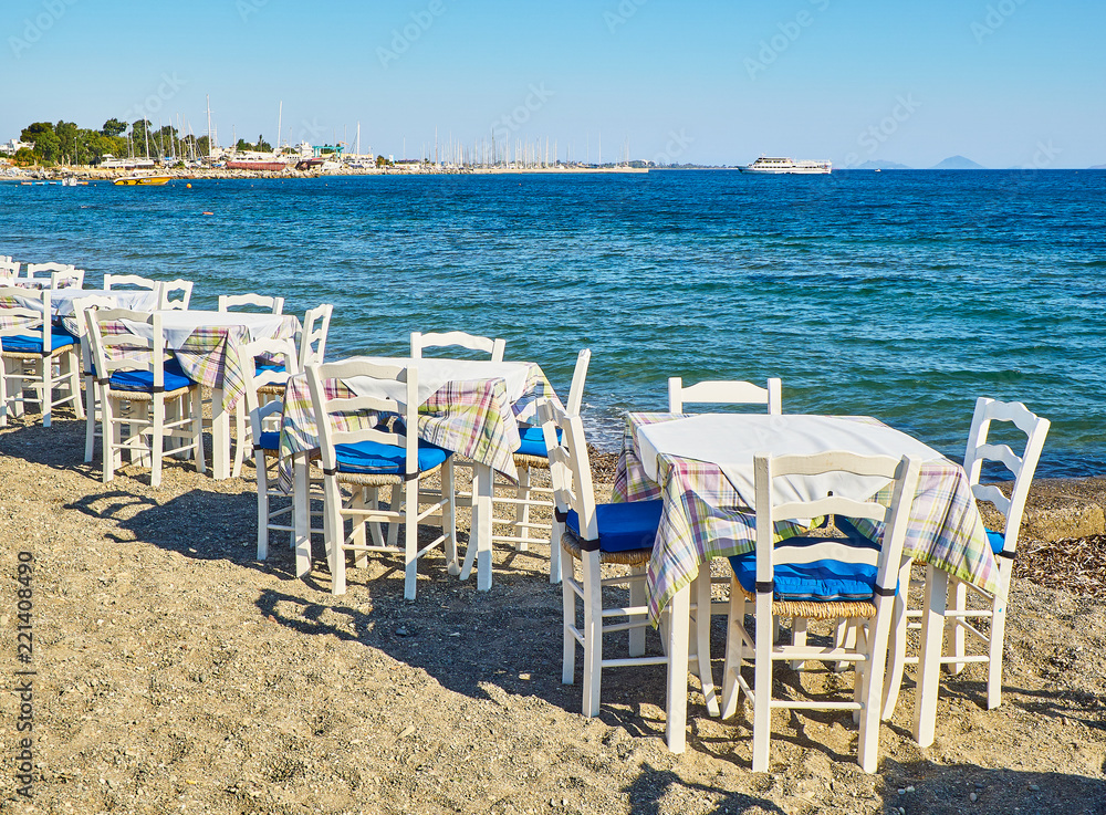 A table with chairs of a greek tavern near the sea in a beach of Kos island, Greece.