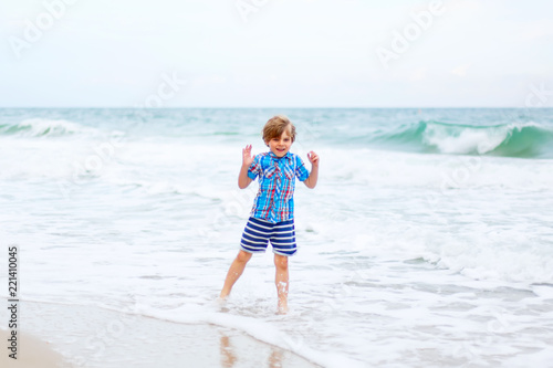Portrait of happy little kid boy on the beach of ocean. Funny cute child making vacations and enjoying summer.. © Irina Schmidt