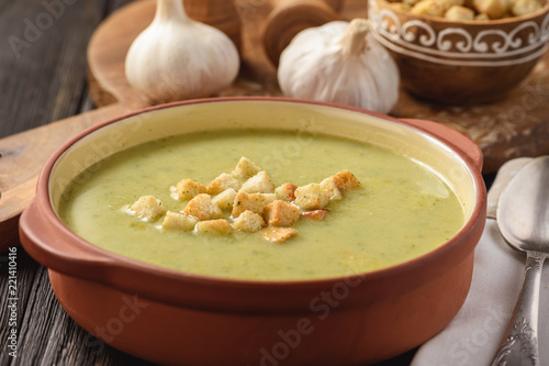 Broccoli cream soup with croutons on wooden background.
