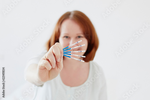 Happy young woman with many positive pregnancy tests
