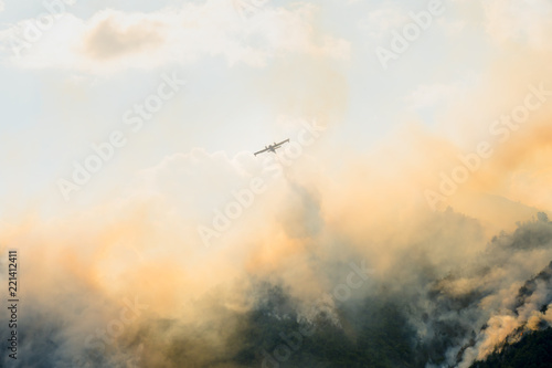 Aerial firefighting with Canadair plane on a big wildfire. Firemen on a water bomber aircraft fighting flames in forest.