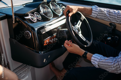 Aspirational successful mid-aged caucasian businessman sitting behaind the wheel of speed motorboat, driving at open sea, enjoying with speed. photo