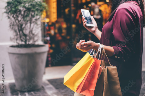 Consumerism, shopping, lifestyle concept, Young woman holding colorful shopping bags and smartphone enjoying in shopping