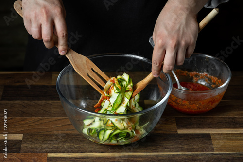 Chef cooking zucchini Italian dish cooking with cheese and tomato sauce, steps on black background kitchen.