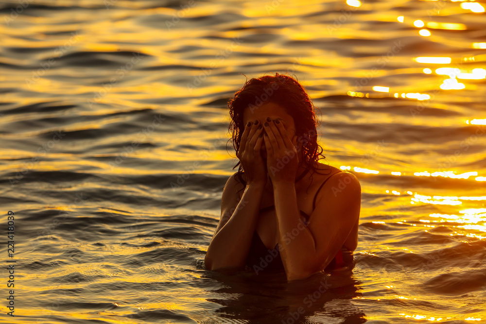 Fototapeta premium A girl is floating in the sea at sunset