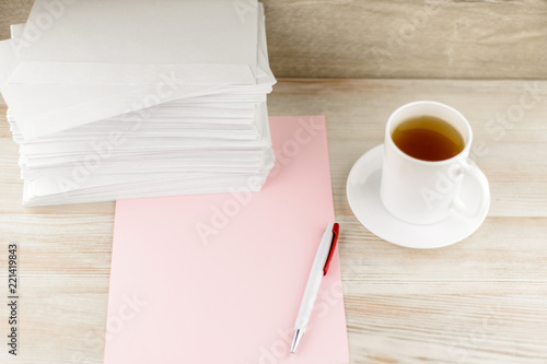 everyday life of an office worker - monotonous stack of envelopes, a sheet of pink paper and pen lie ahead on the desktop, with a fresh Cup of green tea is next