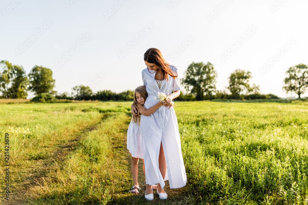 beautiful mother and daughter embracing in green meadow on sunset beautiful mother and daughter embracing in green meadow on sunset