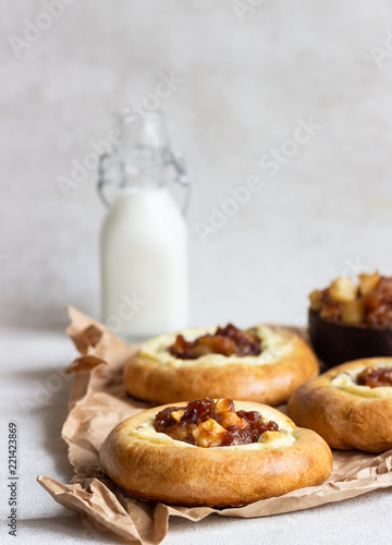 Fresh homemade open yeast buns with cottage cheese and caramel apple (traditional Russian pastry vatrushka, round buns, curd tart) on light grey background. Sweet rolls. Selective focus. Rustic style.