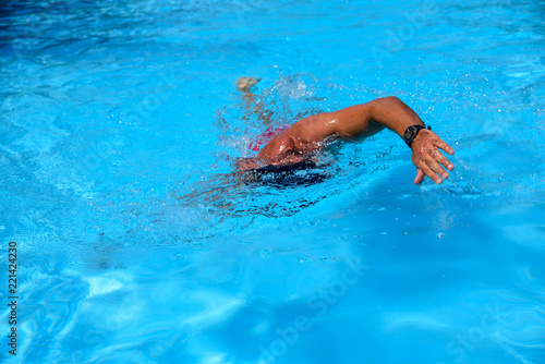 Caucasian man swims in freestyle  crawl  at the outdoor swimming pool on a sunny summer day